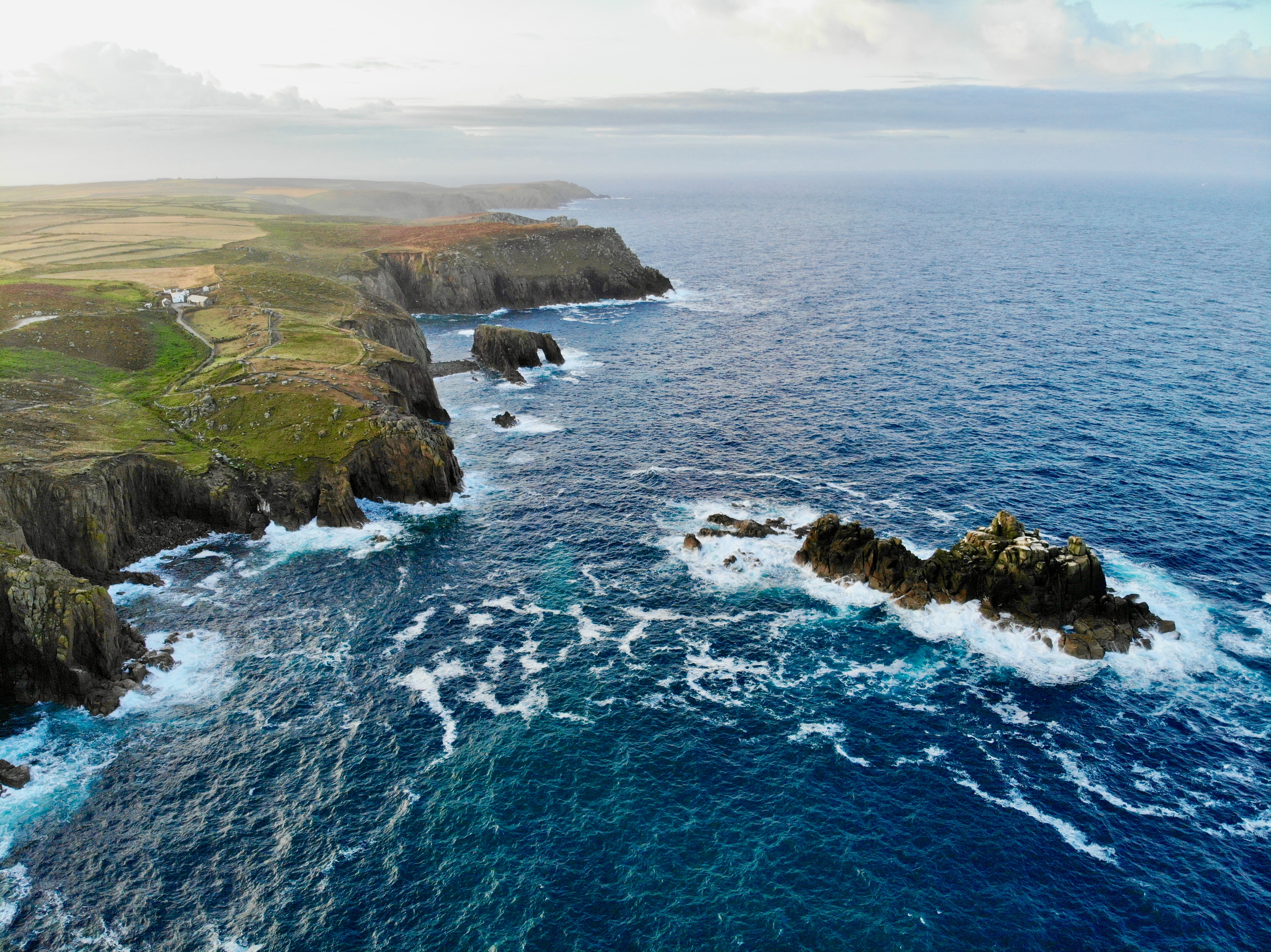 A coastline with waves and rolling hills and rocks.